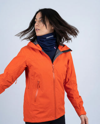 Femme en veste orange avec tour de cou Pavenrod bleu marine (laine mérinos, nylon recyclé), protection froid et vent en montagne, fabriqué en France.