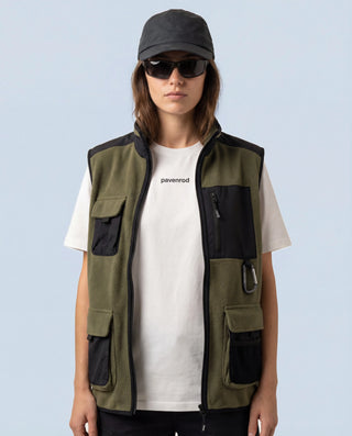 Portrait femme portant le t-shirt blanc Pavenrod en coton biologique, fabriqué en France, sous un gilet outdoor sur fond bleu clair.