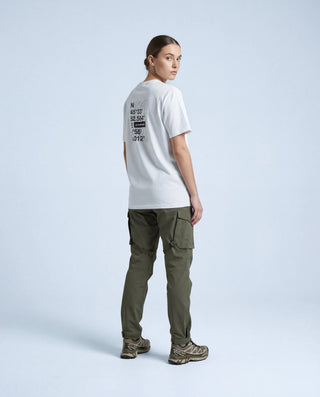 Femme portant t-shirt outdoor Pavenrod blanc en coton bio, fabriqué en France, vue dos trois-quarts, graphisme coordonnées, fond studio.