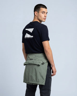 Homme portant t-shirt outdoor Pavenrod noir en coton bio, fabriqué en France, vue dos trois-quarts, fond studio clair.