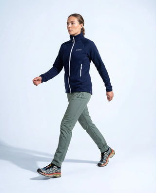 Vue de profil : femme marchant, veste polaire zippée Pavenrod bleu marine en laine, vêtement outdoor fabriqué en France.